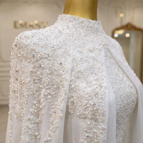 Close-up of the crystal and pearl beadwork on the Aurelia modest wedding gown with chiffon cape by EMANY
