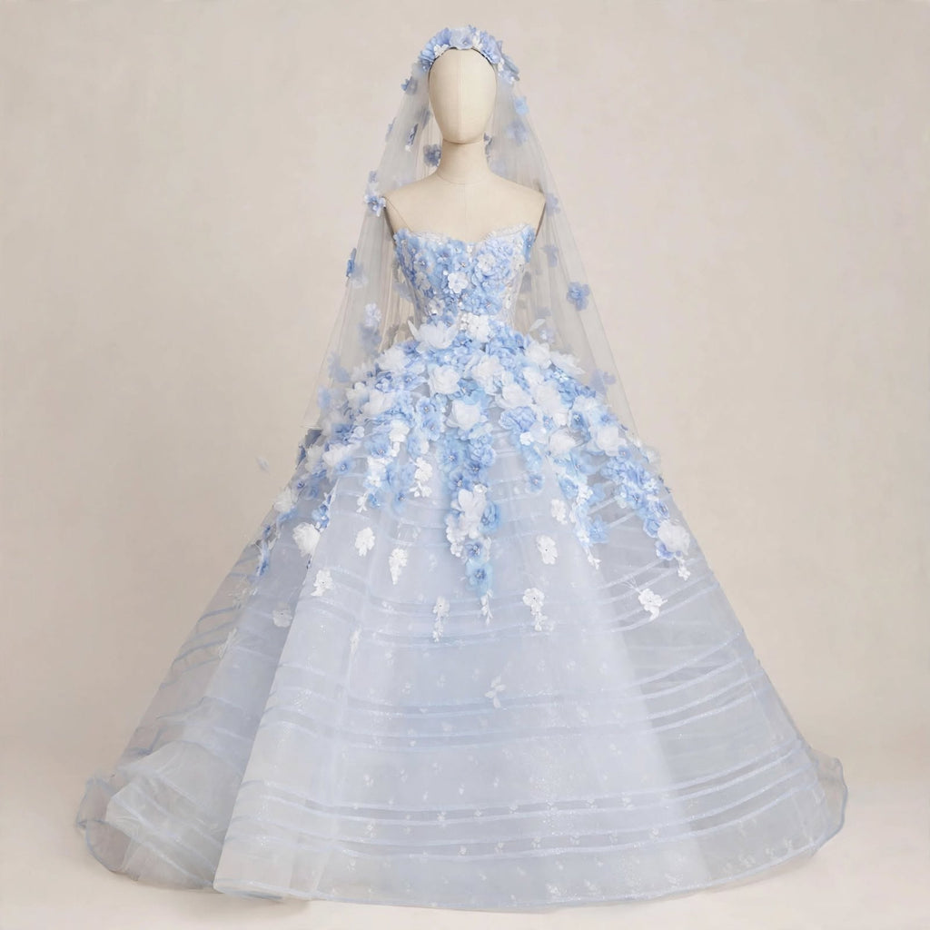 Light blue ball gown wedding dress with white and blue 3D floral appliqués, sheer corset bodice, and a matching floral cathedral veil displayed on a mannequin.

