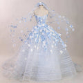 Light blue ball gown wedding dress with white and blue 3D floral appliqués, sheer corset bodice, and a matching floral cathedral veil displayed on a mannequin.

