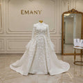 Full front view of the Lumière royal modest wedding dress by EMANY, featuring a high neck, 3D floral details, and a dramatic tulle overskirt.

