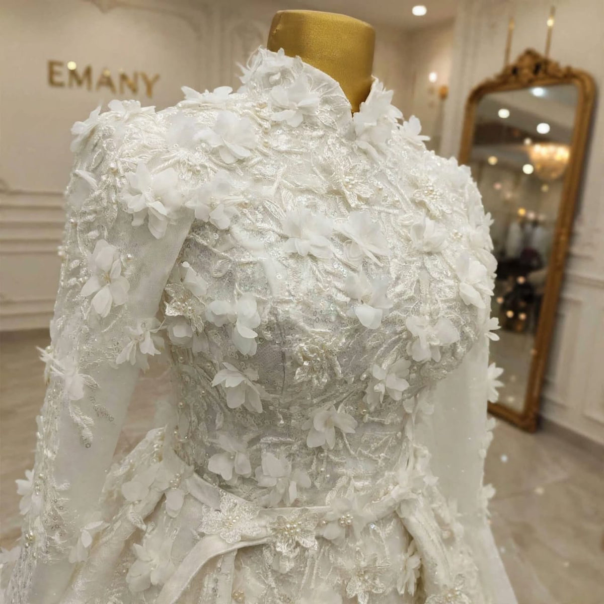 Detailed view of the high collar, embellished sleeves, and floral appliqués on the Lumière modest royal dress.

