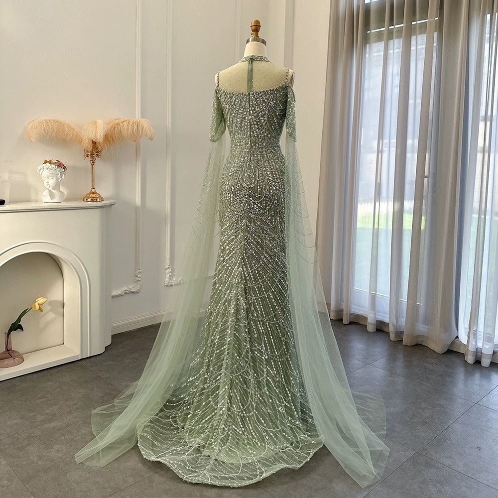 Luxury beaded mermaid evening gown with a high neck, sheer illusion bodice, and flowing tulle cape sleeves displayed on a mannequin in green and mauve.

