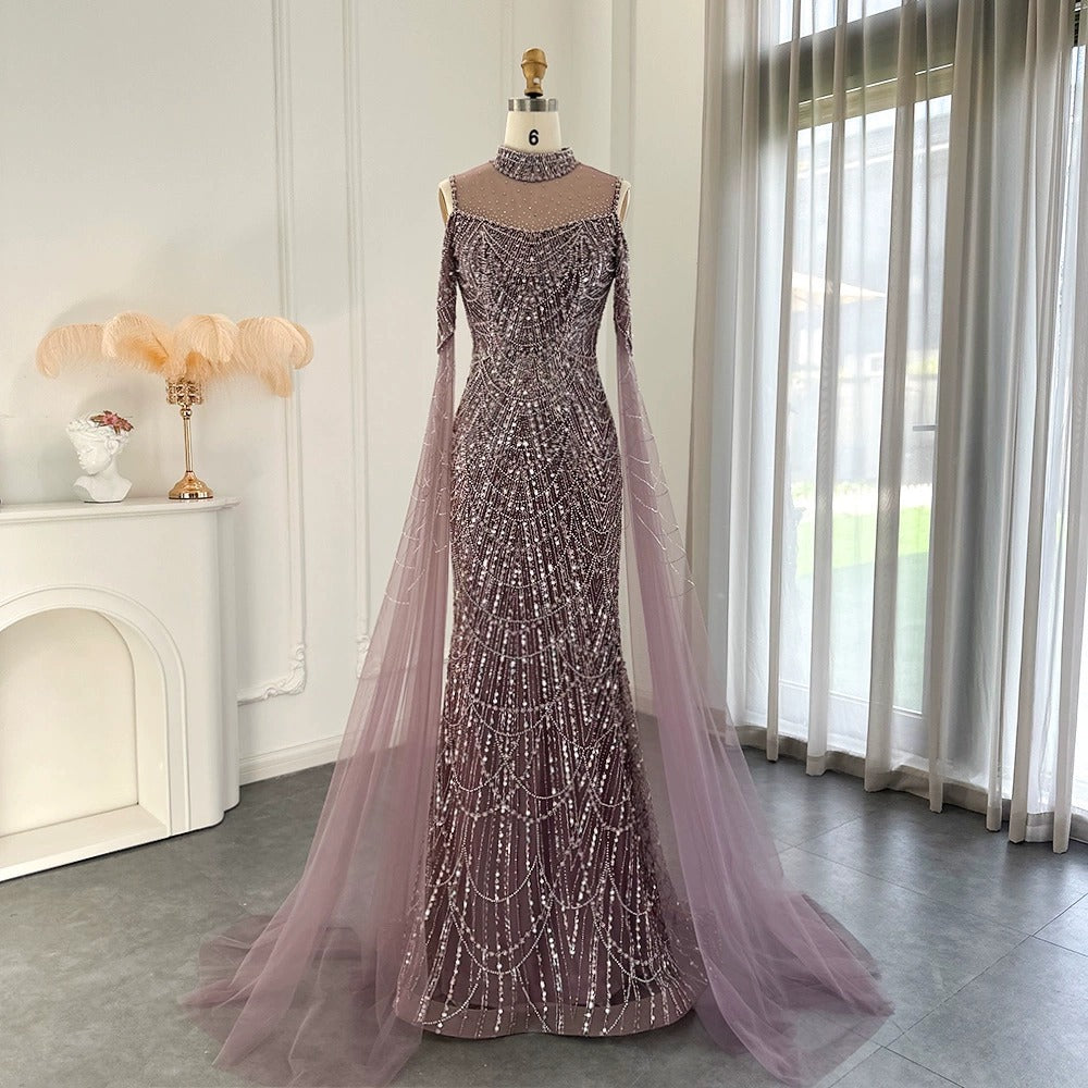 Luxury beaded mermaid evening gown with a high neck, sheer illusion bodice, and flowing tulle cape sleeves displayed on a mannequin in green and mauve.

