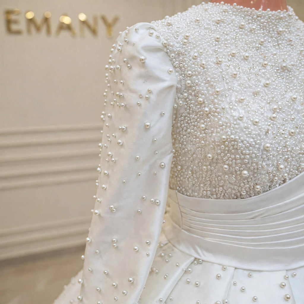 Close-up of the pearl-embellished bodice and long sleeves on the Marguerite modest wedding gown by EMANY.