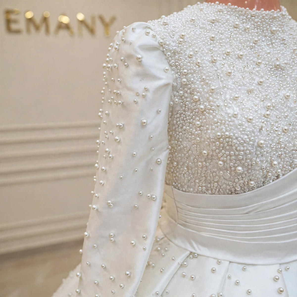 Close-up of the pearl-embellished bodice and long sleeves on the Marguerite modest wedding gown by EMANY.