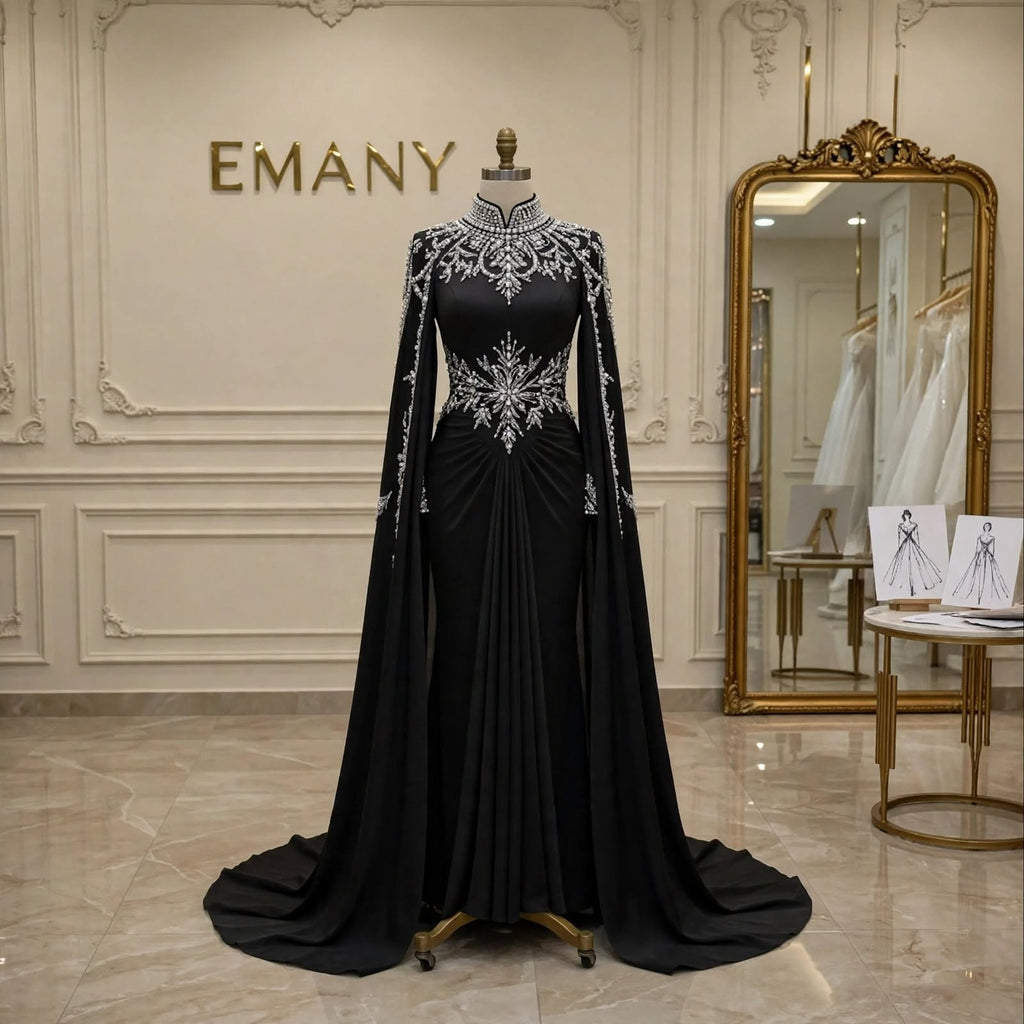 Front full view of the Noor Noir modest black mermaid gown with dramatic cape sleeves by EMANY.

