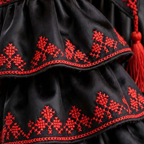 Close-up of the red floral embroidery and tiered ruffle sleeves on the Sultana royal dress by EMANY.

