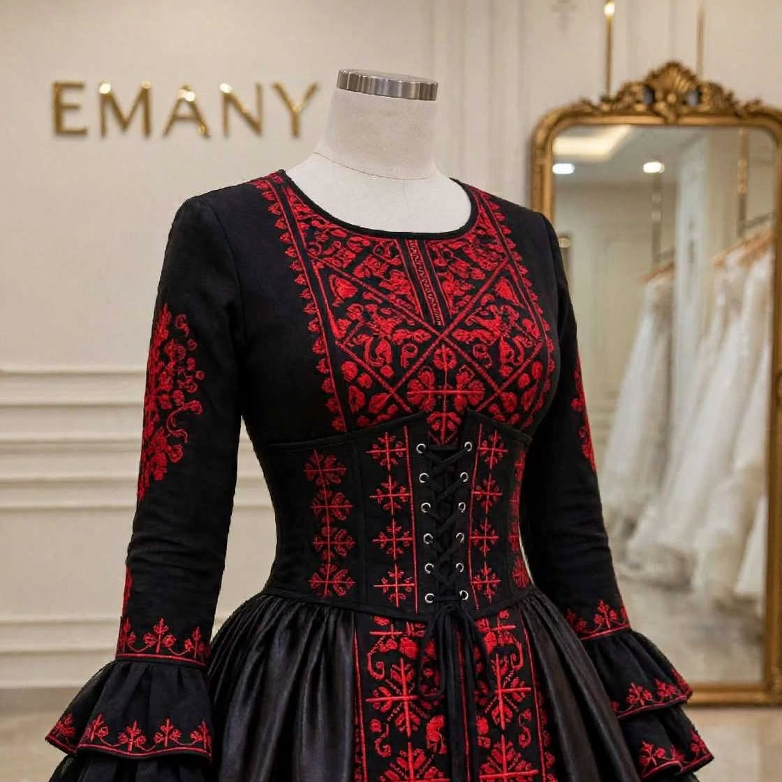 Macro shot of the authentic red geometric and floral embroidery on black fabric of the Sultana couture gown.

